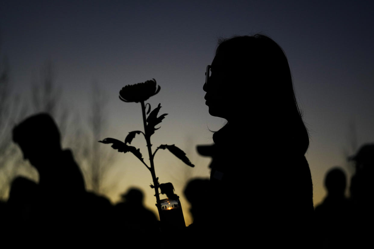 A woman holds a candle and a flower during a vigil outside Monterey Park City Hall, blocks from the Star Ballroom Dance Studio, late Tuesday, Jan. 24, 2023, in Monterey Park, Calif. A gunman killed multiple people at the ballroom dance studio late Saturday amid Lunar New Year's celebrations in the predominantly Asian American community. (AP Photo/Ashley Landis)