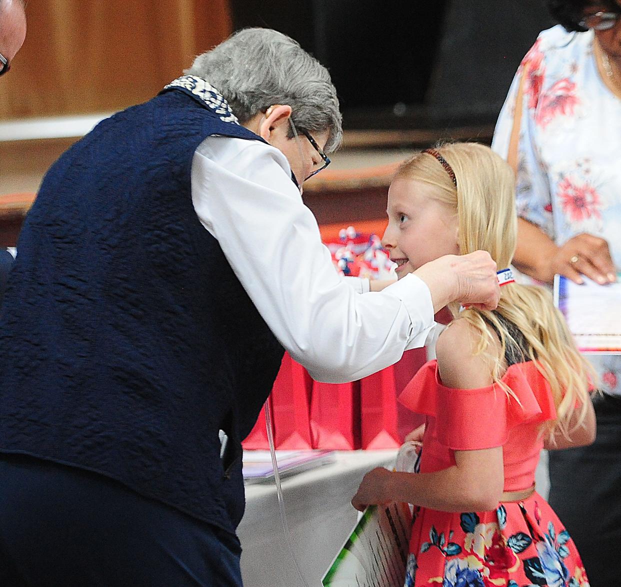 Harper Ritchie receives a medal and congratulations from Quota Club President Helen Bosick on Saturday, April 27, 2024, during the Sparkles Awards Cookie Reception at The Commons in Alliance.