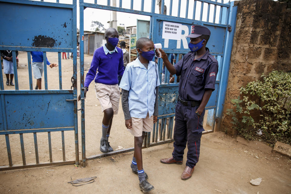 Schoolchildren have their temperature taken as they arrive at the Olympic Primary School in Kibera, one of the capital Nairobi's poorest areas, in Kenya Monday, Oct. 12, 2020. Kenya partially re-opened schools on Monday to allow those students due for examinations which had been postponed to prepare, following a total closure of all educational institutions enacted since March to curb the spread of the coronavirus pandemic. (AP Photo/Brian Inganga)