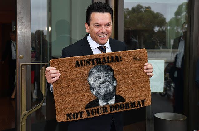 Nick Xenophon arrives at Parliament House in Canberra, holding a novelty doormat. Picture: Mick Tsikas/AAP Image