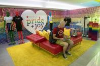 In this Thursday, June 20, 2019, photo, a customer takes a break from shopping at the Pride and Joy shop in the Macy's flagship store in New York. For Pride month, retailers across the country are selling goods and services celebrating LGBTQ culture. Macy’s flagship store is adorned with rainbow-colored Pride tribute windows, set in the same space as its famous Christmas displays. (AP Photo/Mary Altaffer)