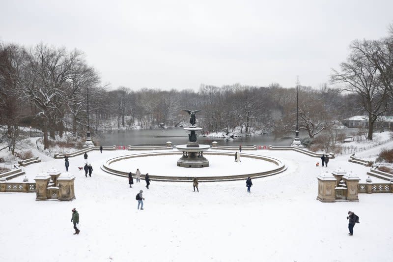 Pedestrians gather in Central Park as snow falls accompanied by cold temperatures in New York City on Tuesday. Photo by John Angelillo/UPI