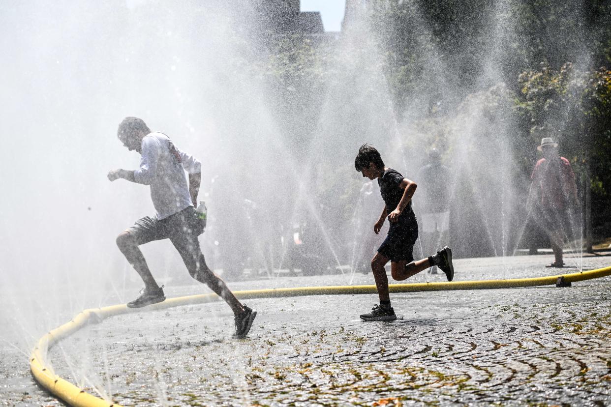 A man and his son cool down in the spray coming from water hoses in the city of Cologne, in western Germany.