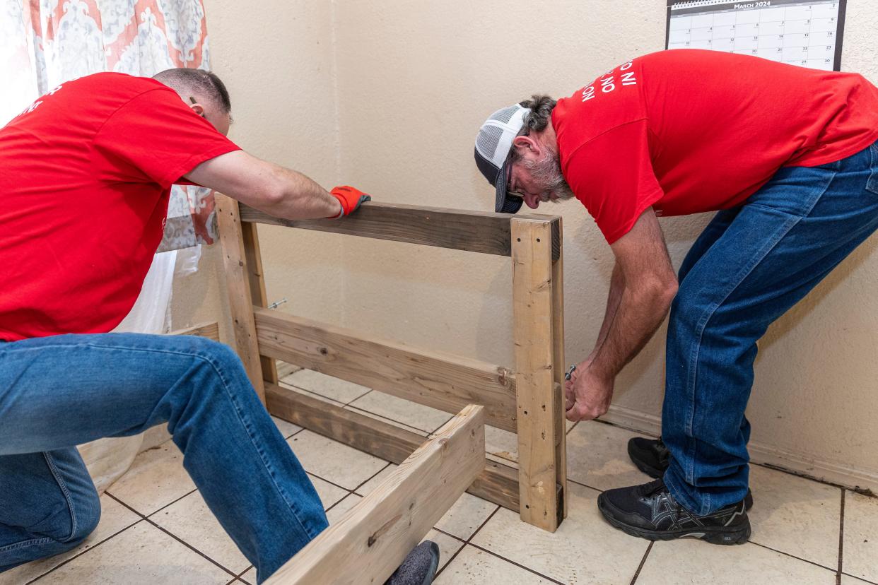 Sleep in Heavenly Peace volunteers Todd Taylor, left, and Rich Moio, right, assemble a bed at a family's home.