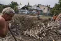 Workers clear debris next to a crater caused by a rocket strike on a house in Kramatorsk, Donetsk region, eastern Ukraine, Friday, Aug. 12, 2022. There were no injuries reported in the strike. (AP Photo/David Goldman)