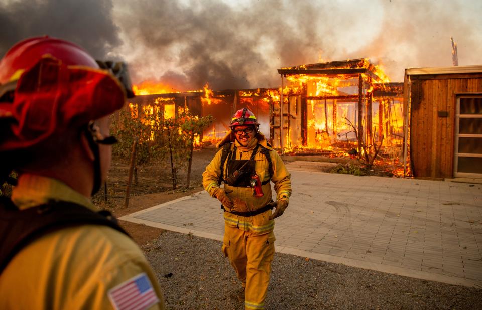 Fire Captain Rico Ramirez chats with firefighters as they assess the scene of a burning home during the Kincade fire in Healdsburg, California on October 27, 2019. - Powerful winds were fanning wildfires in northern California in "potentially historic fire" conditions, authorities said October 27, as tens of thousands of people were ordered to evacuate and sweeping power cuts began in the US state. (Photo by Josh Edelson / AFP) (Photo by JOSH EDELSON/AFP via Getty Images)