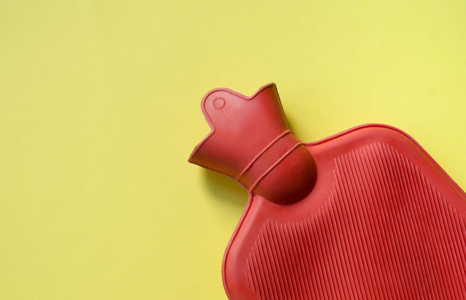 Red hot water bottle on yellow background