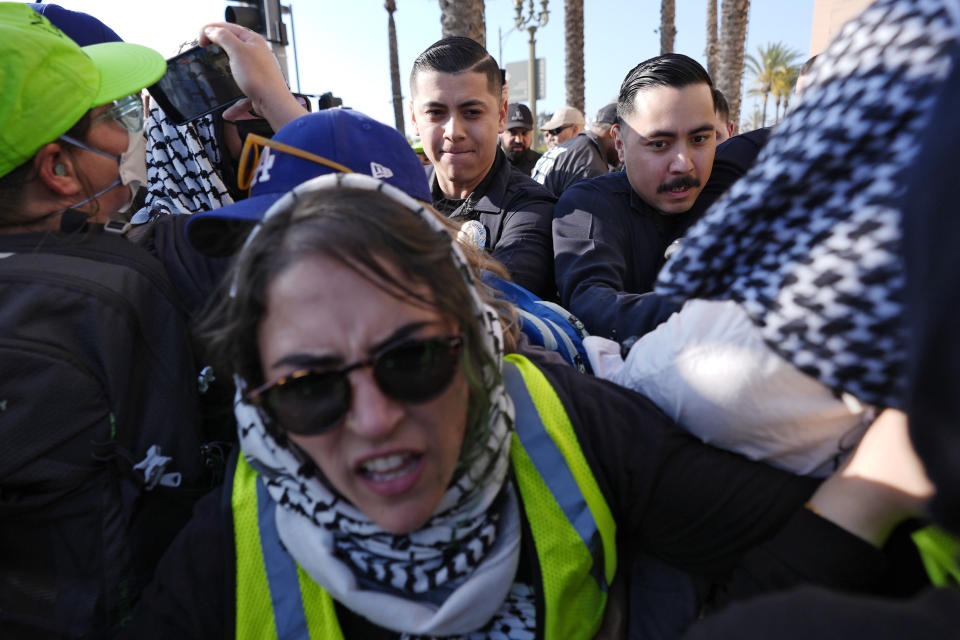Los Angeles Police Department officers push aside pro-Palestinian demonstrators so that attendees can get through at the Shrine Auditorium where a commencement ceremony for graduates from Pomona College was being held, Sunday, May 12, 2024, in Los Angeles. (AP Photo/Ryan Sun)