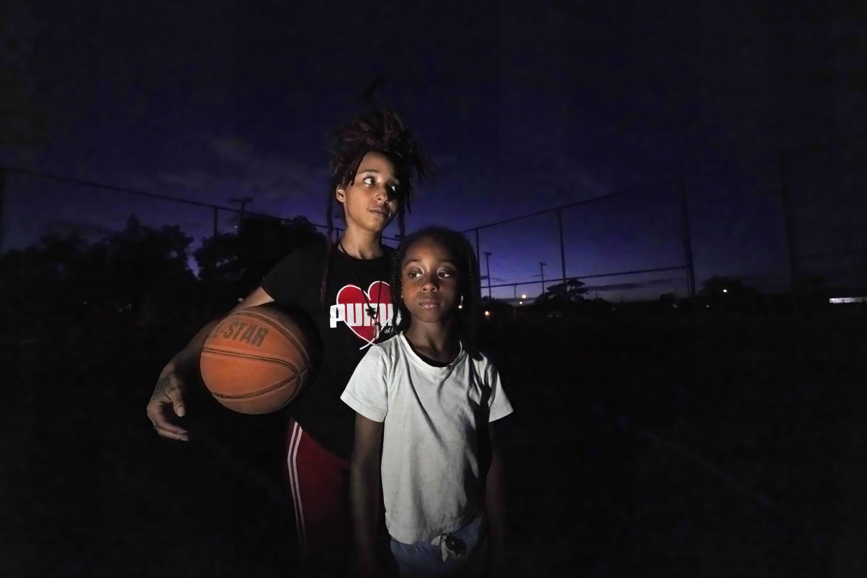 Jada Riley poses with her son Jayden Harris, 6, as they play on a basketball court near her former apartment, Thursday, July 28, 2022, in New Orleans. Two months behind on rent, Riley made the difficult decision last month to leave her apartment rather than risk an eviction judgment on her record. Now, she's living in her car with her 6-year-old son, sometimes spending nights at the apartments of friends or her son's father. (AP Photo/Gerald Herbert)