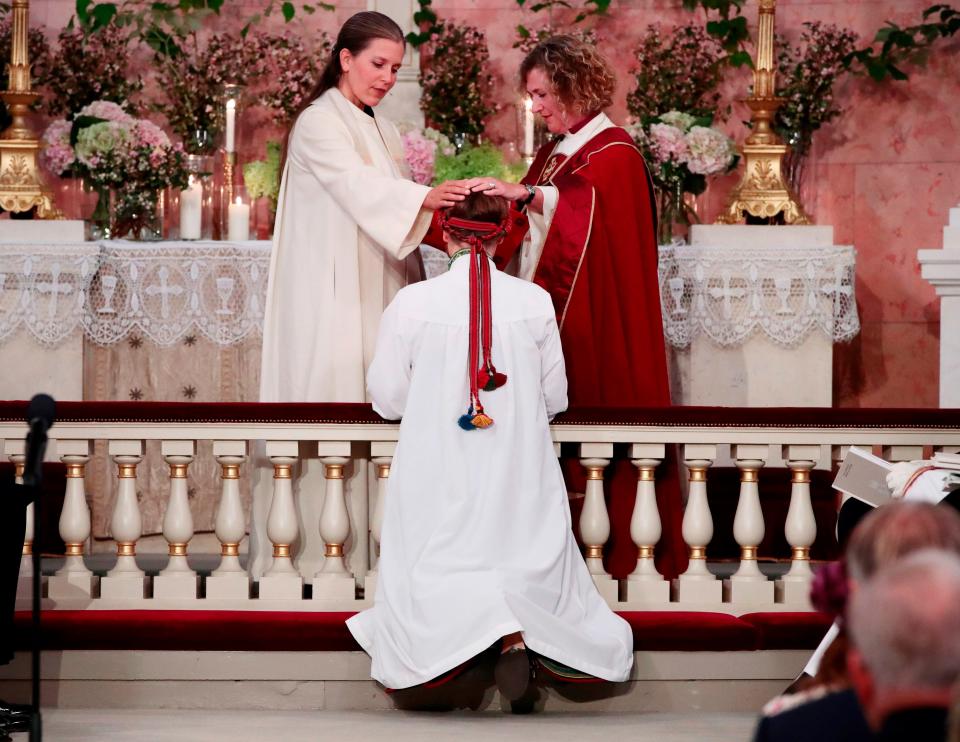 Princess Ingrid Alexandra kneels in front of Vicar Karoline Astrup and Bishop Kari Veiteberg during her confirmation.