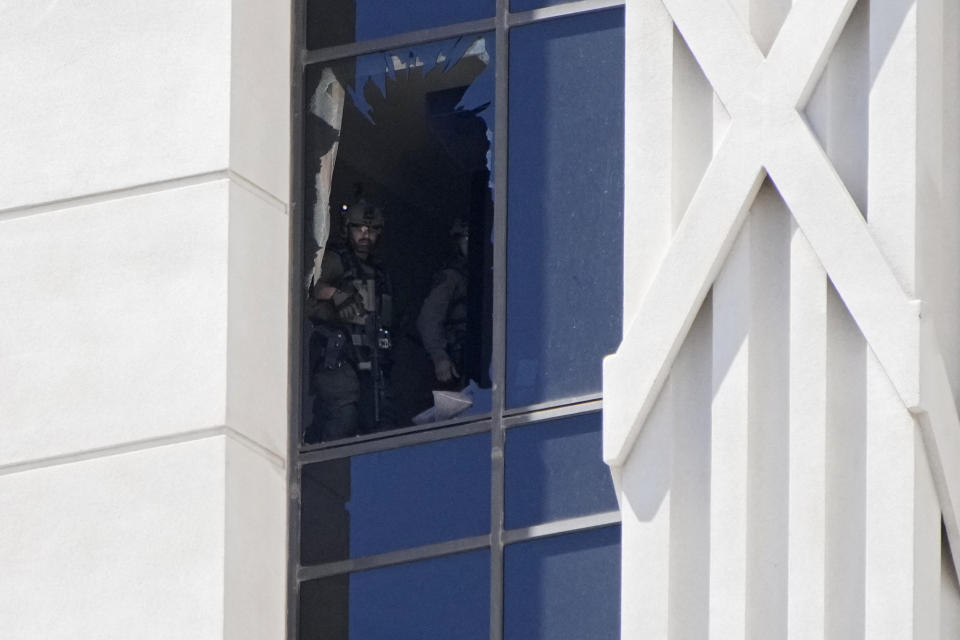A police officer looks out of a broken window on a hotel tower at Caesars Palace hotel-casino, Tuesday, July 11, 2023, in Las Vegas. (AP Photo/John Locher)