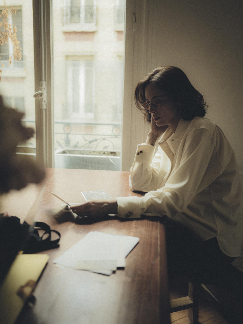 La madre de Anne Berest, Lélia, sostiene postales y retratos familiares que inspiraron el libro de Berest “La postal”. (Julien Mignot for The New York Times).