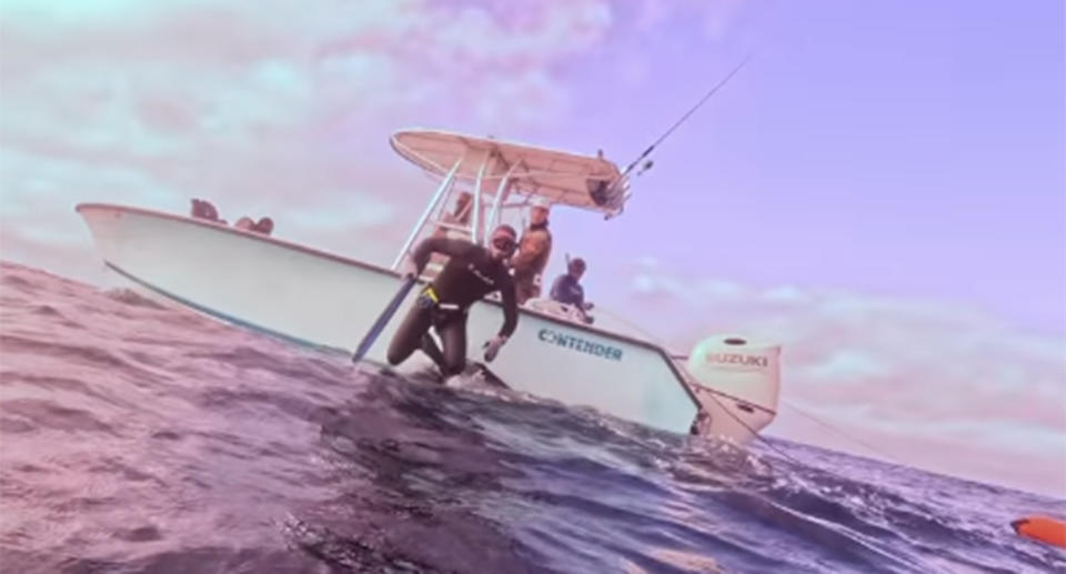 A man jumps off a boat and into the ocean to help his friend who had just been ambushed by a shark.