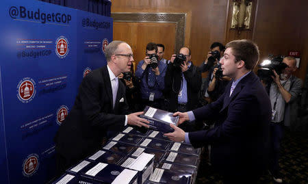 Republican Staff Director of the Senate Budget Committee Eric Ueland (L) hands out a copy of President Trump's Fiscal Year 2018 budget on Capitol Hill in Washington, U.S., May 23, 2017. REUTERS/Kevin Lamarque