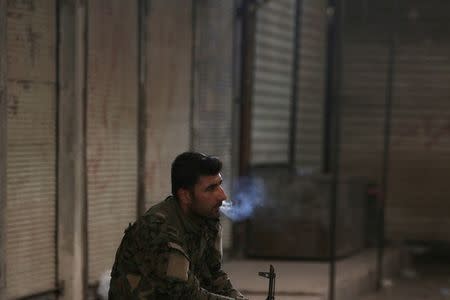 A Syria Democratic Forces (SDF) fighter smokes a cigarette in the city of Manbij, in Aleppo Governorate, Syria, August 10, 2016. REUTERS/Rodi Said