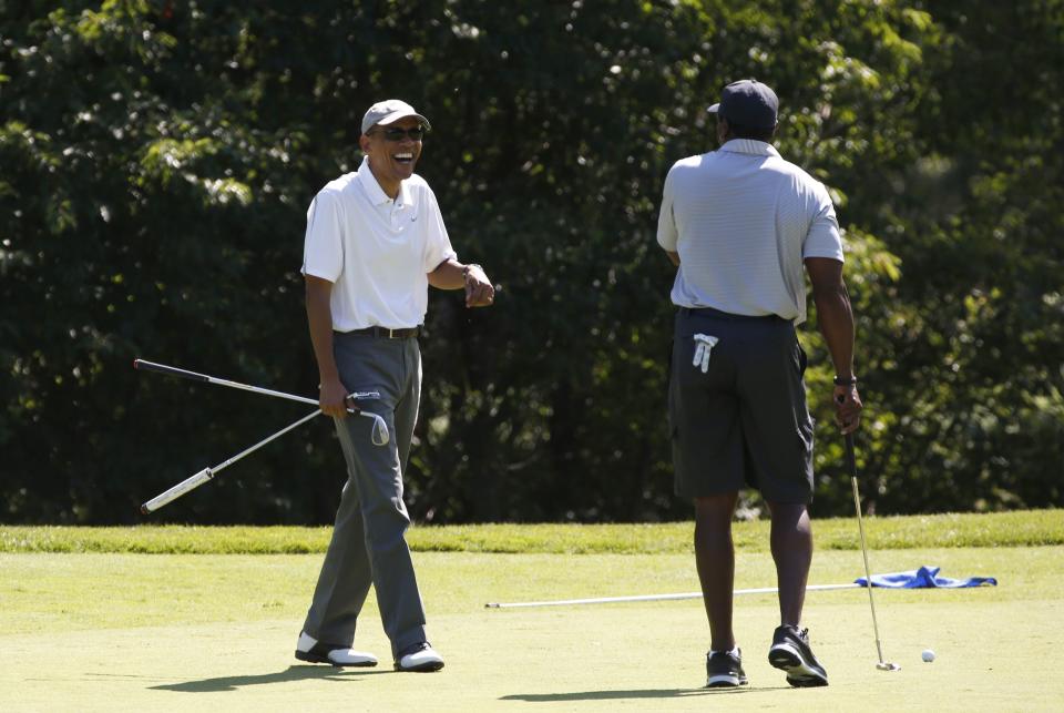 U.S. President Barack Obama laughs with former NFL star Ahmad Rashad (R) while playing a round of golf on Martha's Vineyard in Massachusetts August 9, 2014. The Obama family is taking a two-week vacation on the Vineyard. REUTERS/Kevin Lamarque (UNITED STATES - Tags: POLITICS)