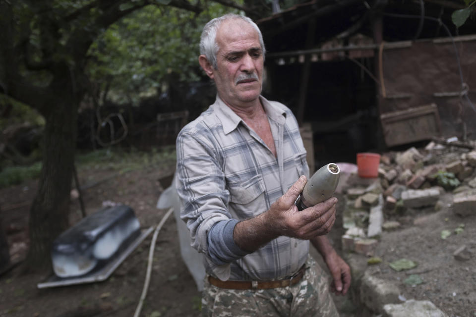 A local resident holds a warhead body that he founded in his yard after an Azerbaijan artillery attack in Hadrut province of self-proclaimed Republic of Nagorno-Karabakh, Azerbaijan, Thursday, Oct. 1, 2020. Two French and two Armenian journalists have been injured in the South Caucasus separatist region of Nagorno-Karabakh, where heavy fighting between Armenian and Azerbaijani forces this week marked the biggest escalation in years of a decades-old conflict. (Karo Sahakyan/ArmGov PAN Photo via AP)