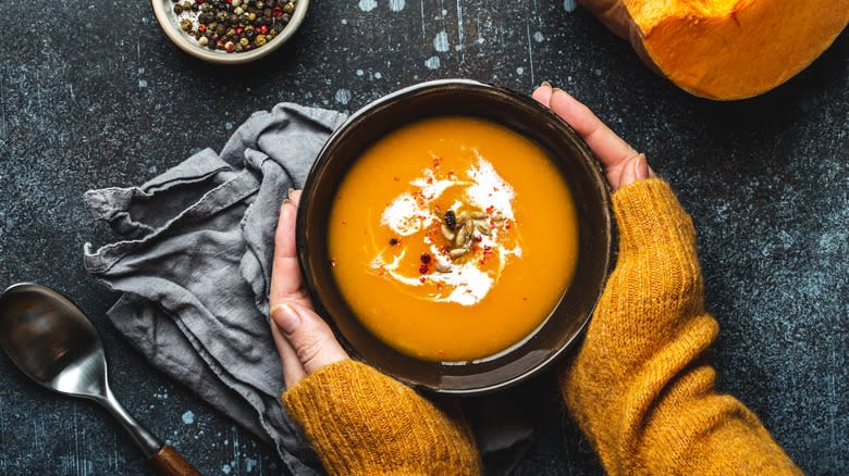 hands around bowl of butternut squash soup