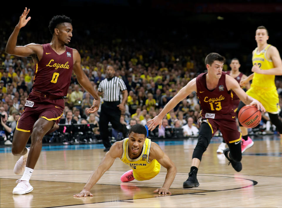 Michigan guard Jaaron Simmons, center, fights for a loose ball with Loyola Chicago’s Donte Ingram, left, and Clayton Custer, right, during the first half in the semifinals of the Final Four NCAA college basketball tournament, Saturday, March 31, 2018, in San Antonio. (AP Photo/Eric Gay)