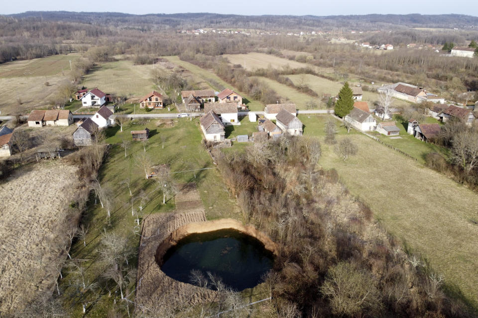 This aerial photo shows a sinkhole in the village of Mececani, central Croatia, Thursday, March 4, 2021. A central Croatian region about 40 kilometers (25 miles) southwest of the capital Zagreb is pocked with round holes of all sizes, which appeared after December's 6.4-magnitude quake that killed seven people and caused widespread destruction. Scientists have been flocking to Mecencani and other villages in the sparsely-inhabited region for observation and study. (AP Photo/Darko Bandic)