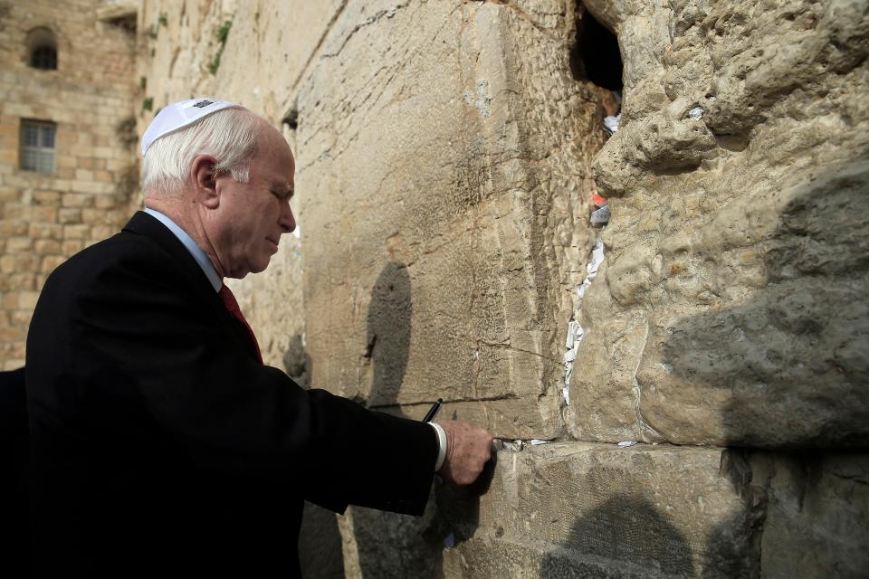 U.S. Senator John McCain places a note in the stones of the Western Wall, the holiest site where Jews can pray during his visit to Jerusalem's old city, Monday, Jan. 19, 2015. People of all faiths slip notes between the stones in the belief that god will answer their prayers. 