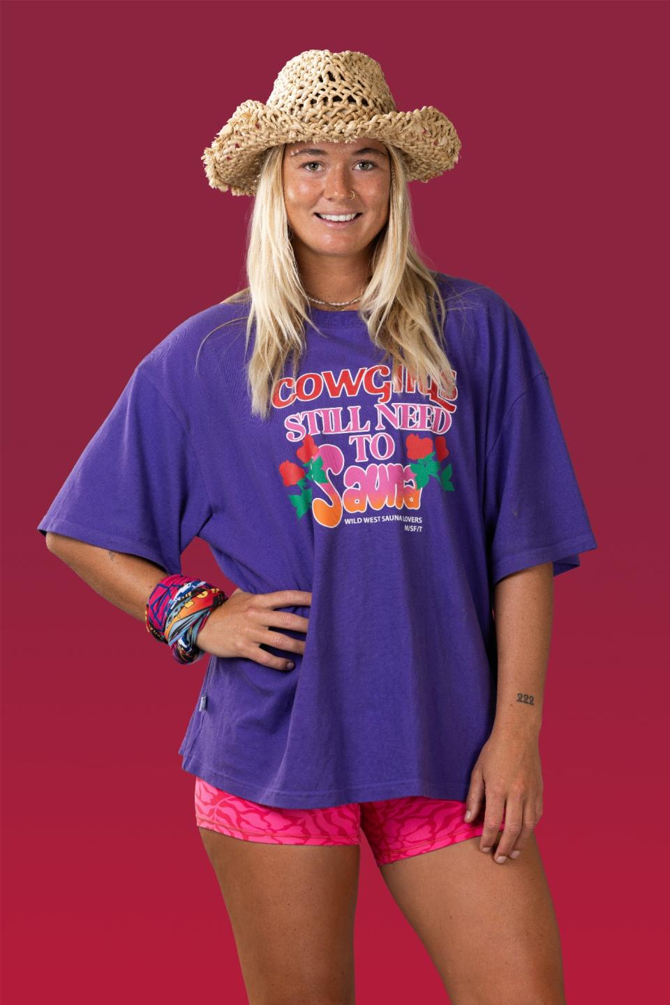 Sarah wears a straw hat, purple t-shirt and pink shorts.