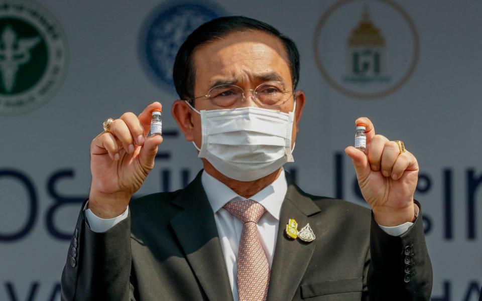 Prime Minister Prayuth Chan-ocha holds samples of the Sinovac vaccine during a ceremony to mark the arrival of 200,000 doses in a shipment at the Suvarnabhumi airport in Bangkok. Prayuth on Wednesday, June 16, 2021, declared that the country is planning to fully reopen to foreign visitors without restrictions by mid-October, as the government seeks to restart the crucial tourist industry,  - AP