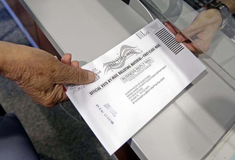 A voter hands in his absentee ballot. (Photo: Alan Diaz/AP)