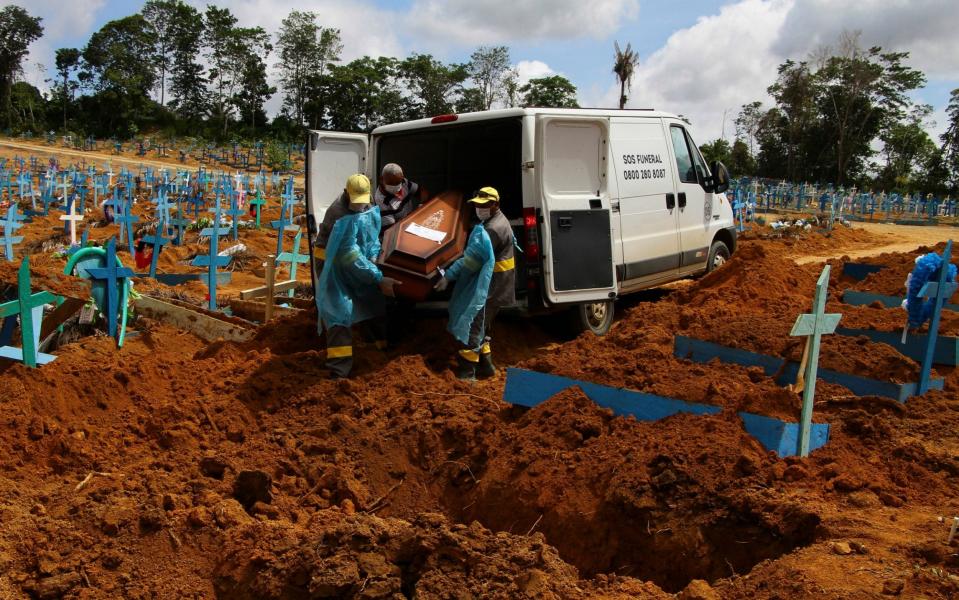 Workers carry a coronavirus victim to be buried at the Nossa Senhora Aparecida cemetery in Manaus - Edmar Barros/AP