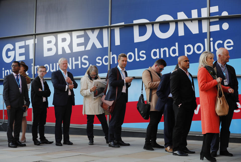 People queue to enter Manchester Central Convention Centre, where Britain's Prime Minister Boris Johnson will later deliver the Leaders's speech at the Conservative Party Conference in Manchester, England, Wednesday, Oct. 2, 2019. Britain's ruling Conservative Party is holding their annual party conference. (AP Photo/Frank Augstein)