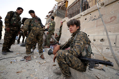 A fighter from Syrian Democratic Forces (SDF) sits on a curb as he holds his weapon in Raqqa, Syria September 25, 2017. REUTERS/Rodi Said