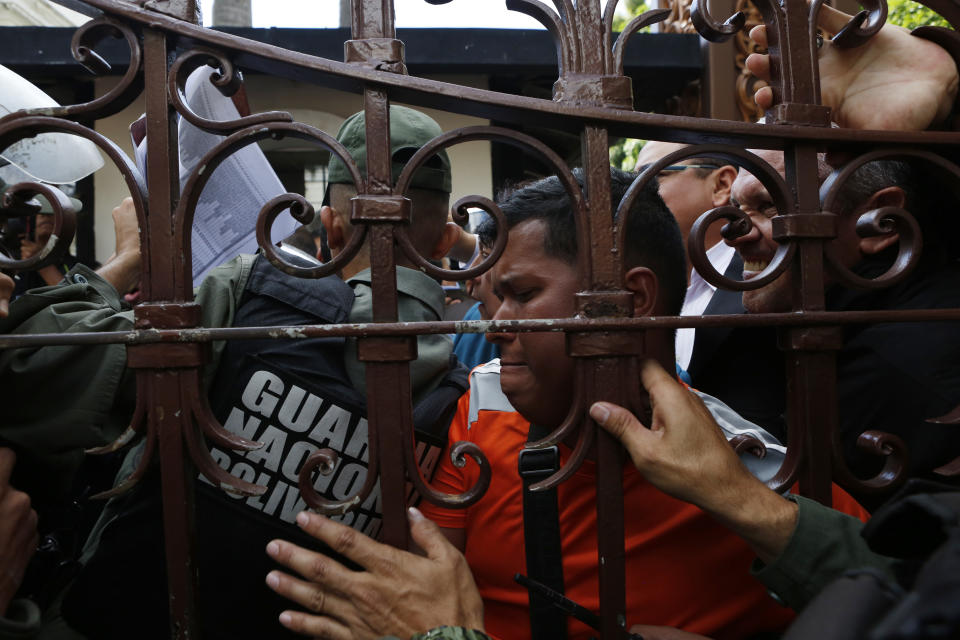 Opposition supporters and lawmakers push through the gate of the National Assembly to enter the grounds in Caracas, Venezuela, Tuesday, Jan. 7, 2020. Opposition leader Juan Guaidó and lawmakers who back him pushed their way into the legislative building on Tuesday following an attempt by rival legislators to take control of the congress, and declared Guaidó the president of the only opposition-controlled institution. (AP Photo/Andrea Hernandez Briceño)