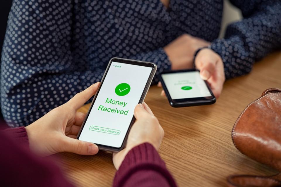 Two people using their smartphones to complete a digital money transfer. 