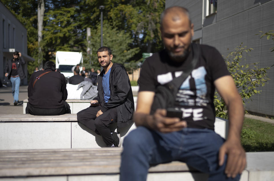 Abdullah al-Shweiti, center, from Homs in Syria, poses for a photo prior to an interview with The Associated Press at the central registration for asylum seekers in Berlin, Germany, Monday, Sept. 25, 2023. The 29-year-old said he had run away from home because his family's house had been bombed in the war and he didn't want to fight in the army. He said he'd paid 3,000 euros, $3,180, to smugglers who helped him get from Lebanon to Europe. (AP Photo/Markus Schreiber)