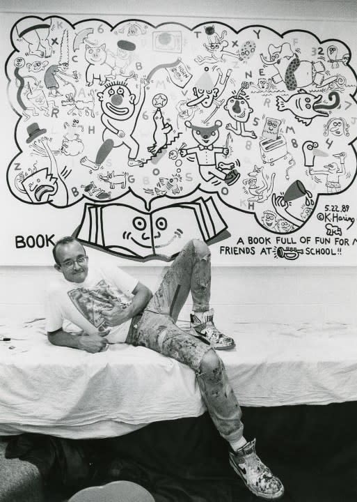 Keith Haring posing with <em>A Book Full of Fun</em>, 1989<em>. </em>Photo by Rodney White. © Keith Haring Foundation
