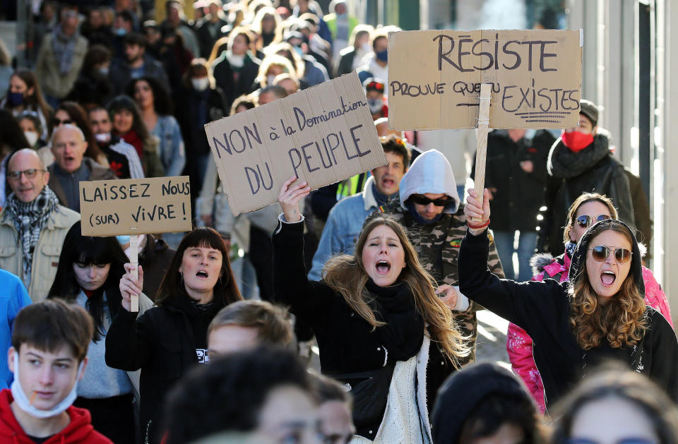 Demonstrators hold placards read " No to the domination of the people" and "Resists" as they protest in Bayonne, southwestern France, Saturday, Nov. 21, 2020. Rights campaigners and journalists organizations staged street protests in Paris and other French cities against a security bill that they say would be a violation of the freedom of information. The proposed measure would create a new criminal offense of publishing images of police officers with intent to cause them harm. (AP Photo/Bob Edme)