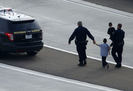 Police officers take care of two boys after an Amber Alert vehicle was stopped on a freeway exit ramp in Santee, California December 11, 2014. REUTERS/Mike Blake