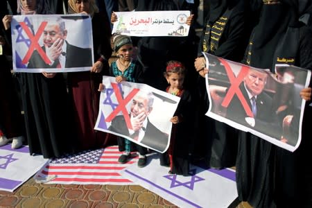 FILE PHOTO: Palestinians hold crossed-out posters depicting U.S. President Trump and Israeli PM Netanyahu during a protest against Bahrain's workshop, in the southern Gaza Strip