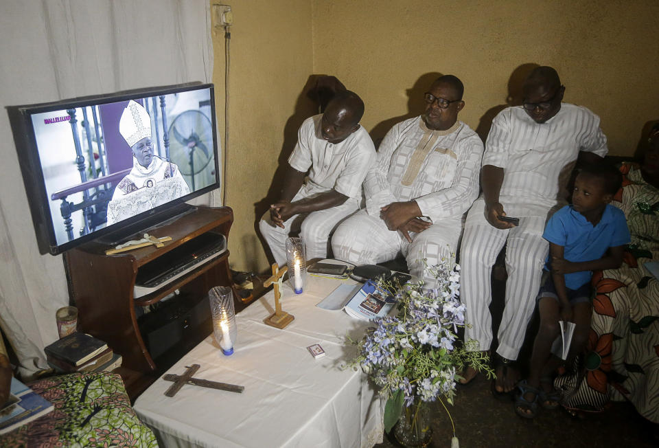 A family under lockdown watches a television broadcast of Archbishop of Lagos Alfred Adewale Martins conducting a service at the Holy Cross Cathedral, in their home in Lagos, Nigeria, on Easter Sunday, April 12, 2020. The new coronavirus causes mild or moderate symptoms for most people, but for some, especially older adults and people with existing health problems, it can cause more severe illness or death. (AP Photo/Sunday Alamba)
