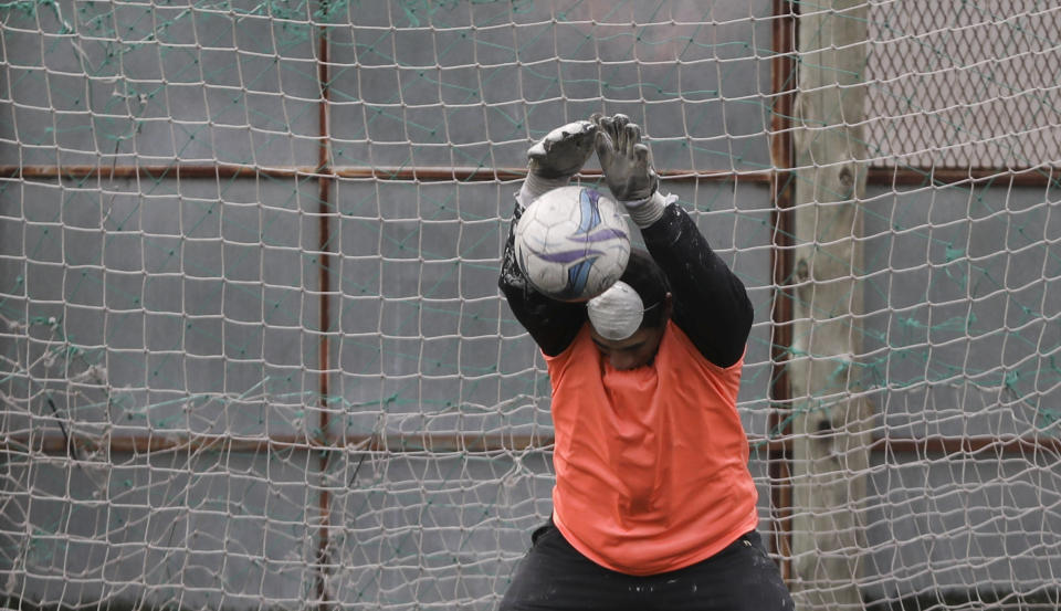 A goalkeeper stops a shot during an amateur soccer match at a local club, Play Futbol 5, in Pergamino, Argentina, Wednesday, July 1, 2020. The club divided a soccer field into 12 rectangles to mark limited areas for each player, keeping them from making physical contact, an adaptation to continue playing amid government restrictions to curb the spread of the new coronavirus. (AP Photo/Natacha Pisarenko)