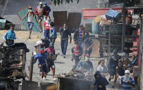 Anti-government protesters clash with security forces as they show support for an apparent mutiny by a national guard unit in the Cotiza neighborhood of Caracas, Venezuela, Monday, Jan. 21, 2019. The uprising triggered protests which were dispersed with tear gas as residents set fire to a street barricade of trash and chanted demands that President Nicolas Maduro leave power. (AP Photo/Ariana Cubillos)