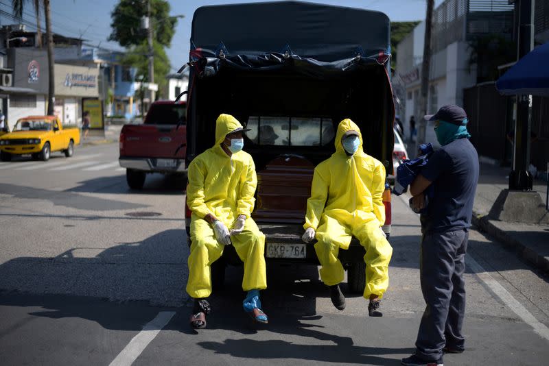 Funeral home workers wearing protective gear wait beside a coffin in a truck outside of Teodoro Maldonado Carbo Hospital amid the spread of the coronavirus disease (COVID-19), in Guayaquil