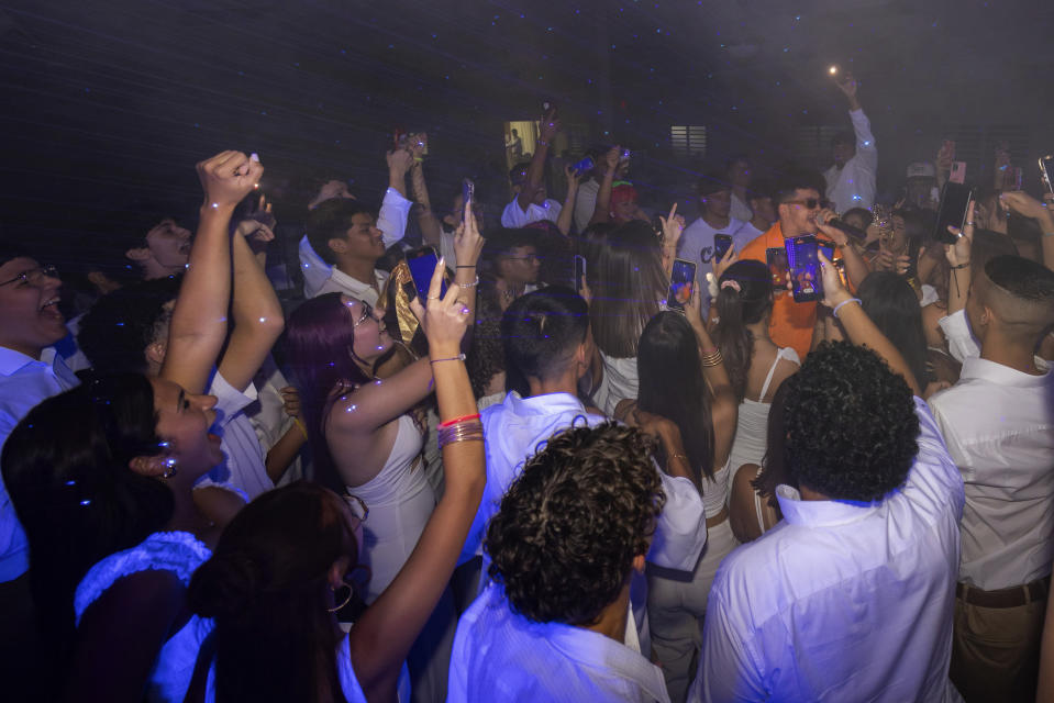 Estudiantes rodean al Dr. Pedro Juan Vázquez, conocido por su nombre artístico PJ Sin Suela, durante su presentación en un baile de graduación de una secundaria en Camuy, Puerto Rico, el jueves 6 de junio de 2024. (Foto AP/Alejandro Granadillo)