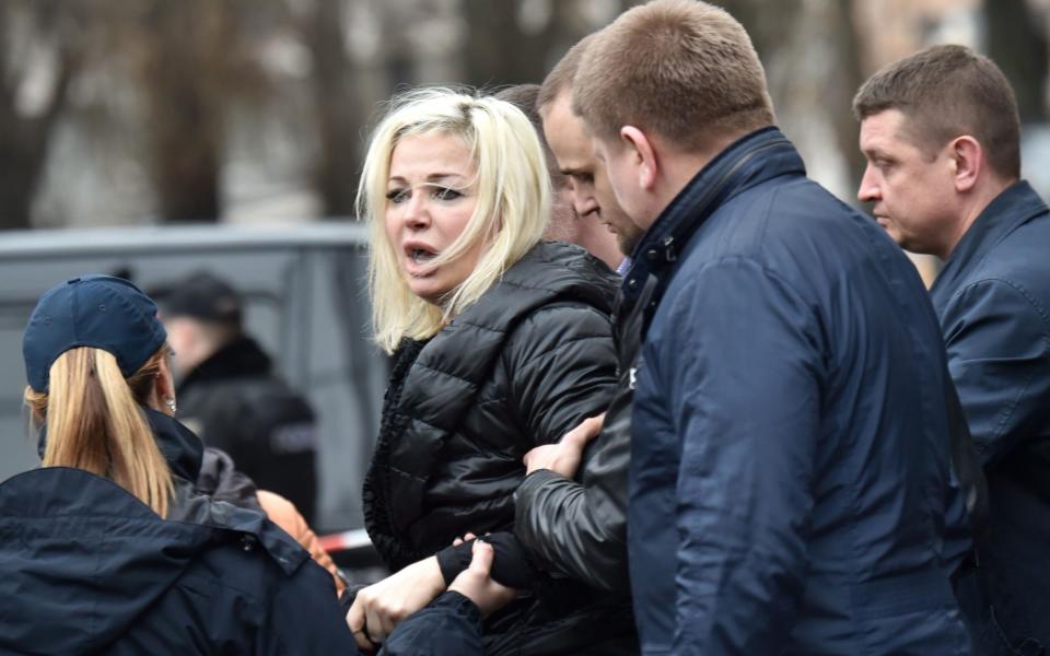 Policemen hold Maria Maksakova at the scene of the murder  - Credit: AFP