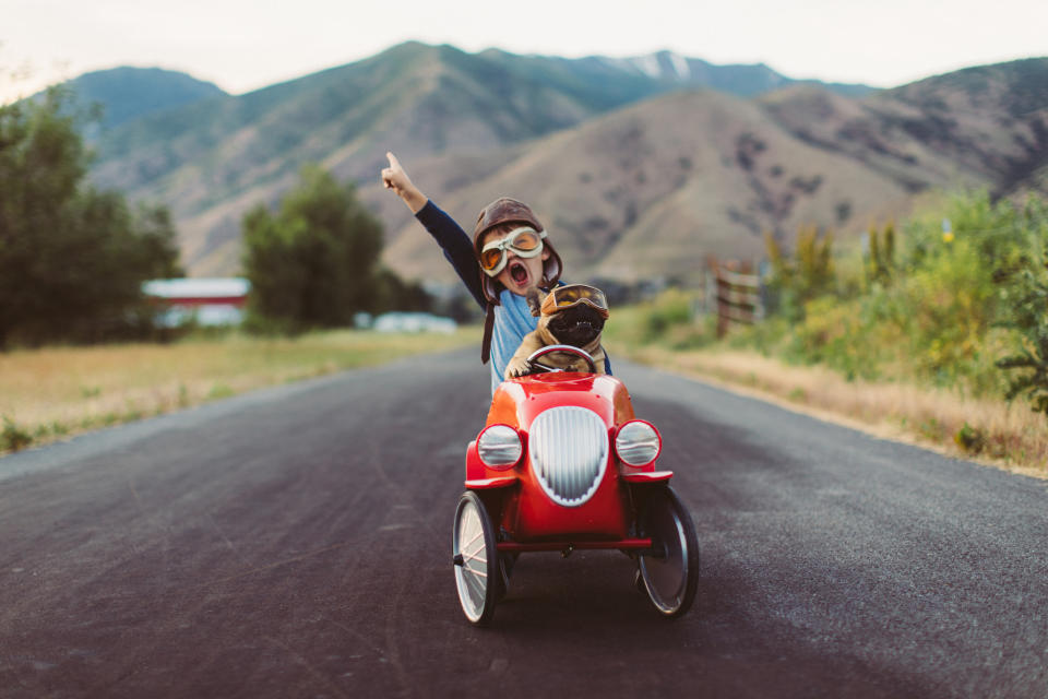 A little kid driving a go cart on the open road screaming in joy.