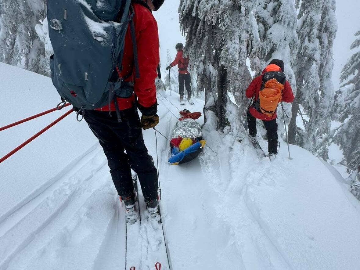 A North Shore Rescue crew moves the avalanche victim down Mount Seymour on a sled. The woman had been trapped under snow for nearly 20 minutes.  (North Shore Rescue - image credit)