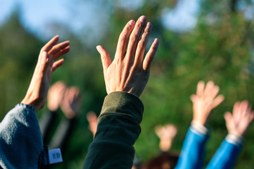 a group of people standing outside while holding their arms and hands up in the air like a cult