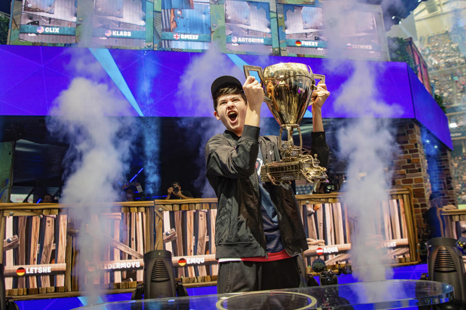 In this Sunday, July 28, 2019 photo, Kyle Giersdorf celebrates as he holds up the trophy after winning the Fortnite World Cup solo finals in New York. Giersdorf, of Pottsgrove, Pa. who goes by the name "Bugha" when competing, racked up the most points and won $3 million as the first Fortnite World Cup solo champion. (Epic Games via AP)