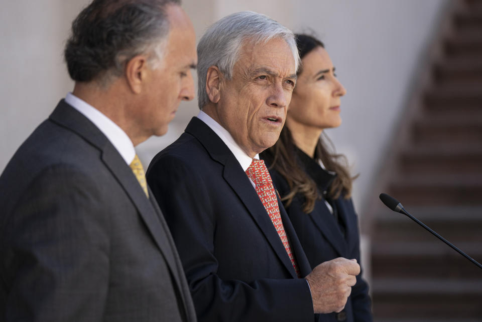 In this photo released by Chile’s presidential office, President Sebastian Pinera, center, accompanied by Chile's Foreign Minister Teodoro Ribera, left, and Environment Minister Carolina Schmidt, announces that he is calling off the Asia-Pacific Economic Cooperation Economic Forum, APEC, and Climate Change COP25 Conference, at La Moneda presidential palace in Santiago, Chile, Wednesday, Oct. 30, 2019. Pinera said that the ongoing protests have led him to call off the two major international summits that his country had been scheduled to host. (Marcelo Segura/Chile's Presidential Office via AP)