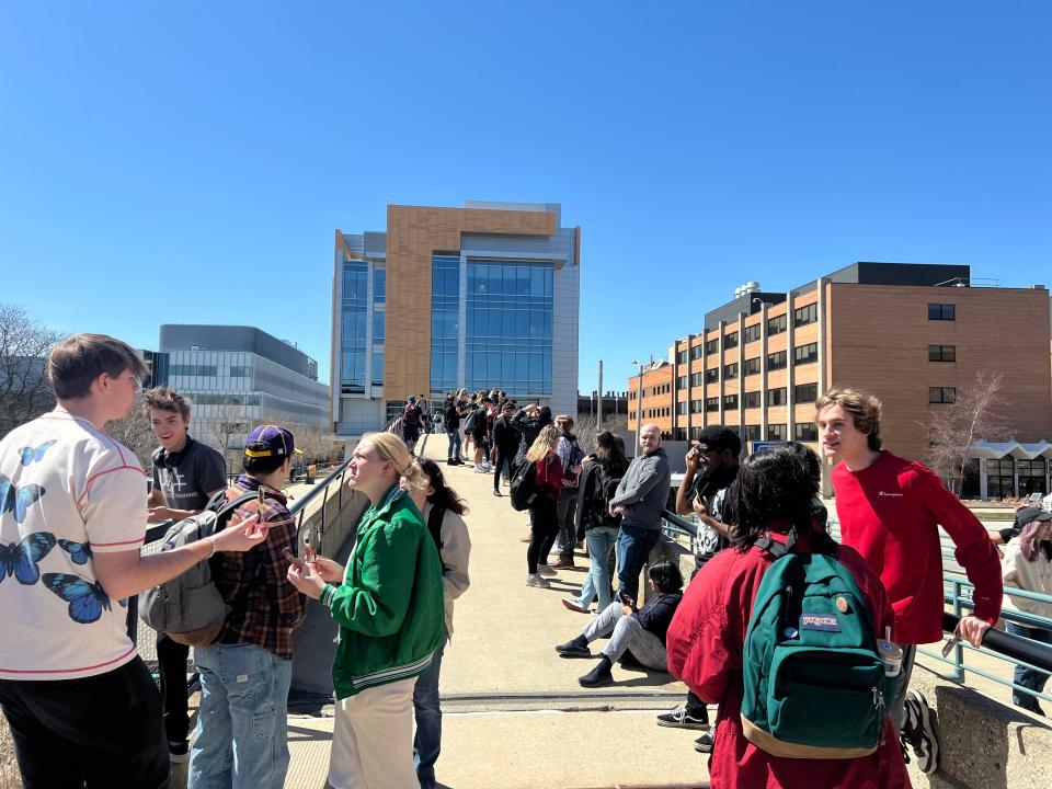 Students and members of the community watch the peak of the partial solar eclipse from the bridge leading into the University of Wisconsin-Milwaukee Student Union.